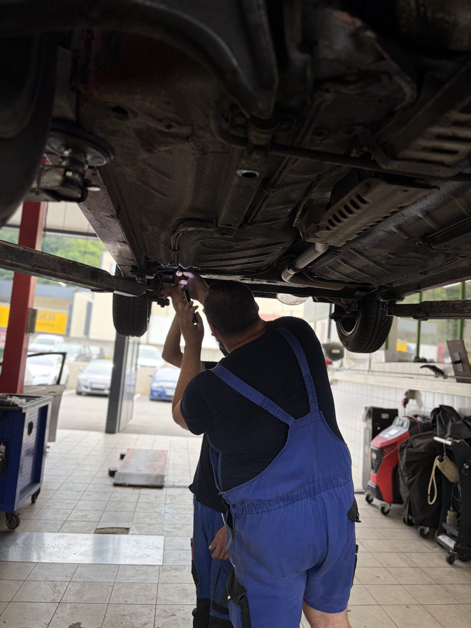 Techniker von KFZ Mack bei der Unterbodenreparatur auf der Hebebühne